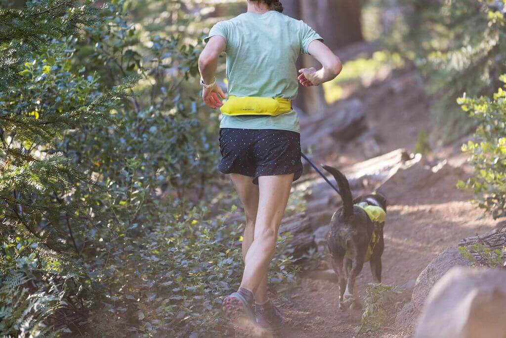 A man wearing Ruffwear's Trail Runner Belt in LIchen Green.  It shows the zipped back pockets on the belt.