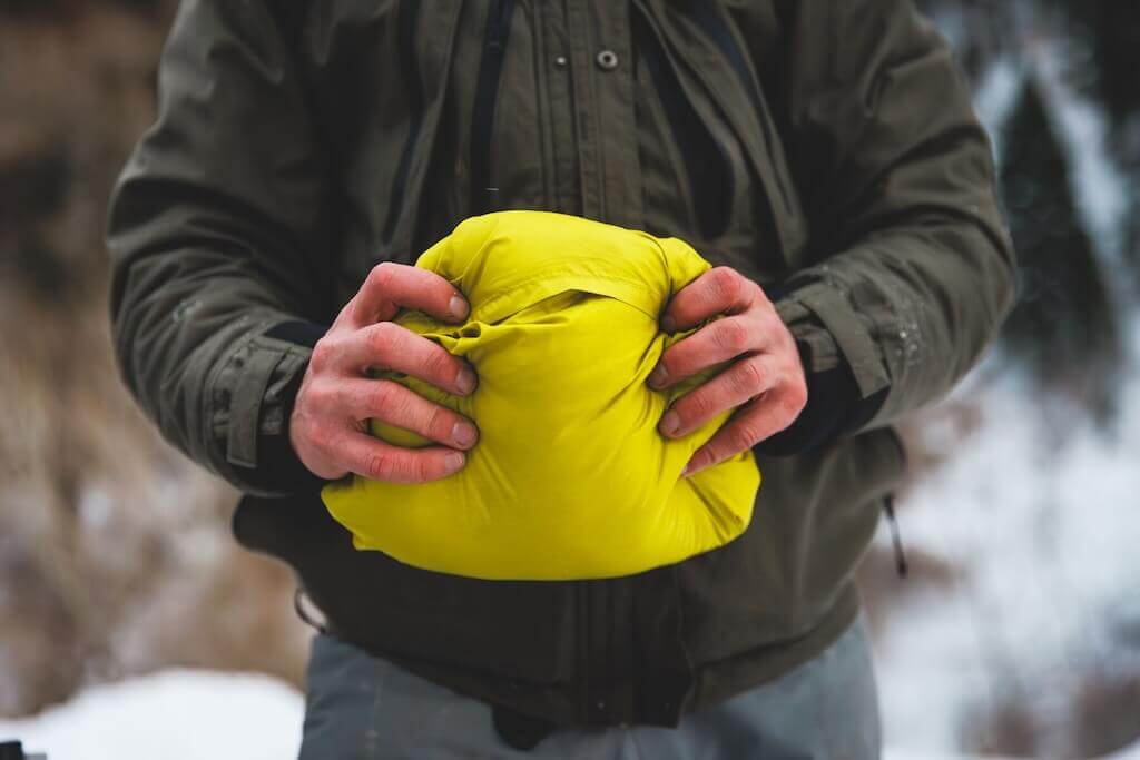 Ruffwear Quinzee Dog Coat in in stuff sack man holding it