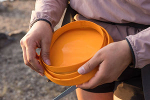 Ruffwear Bivy Bowl in Salamander Orange showing it flat in someones hands